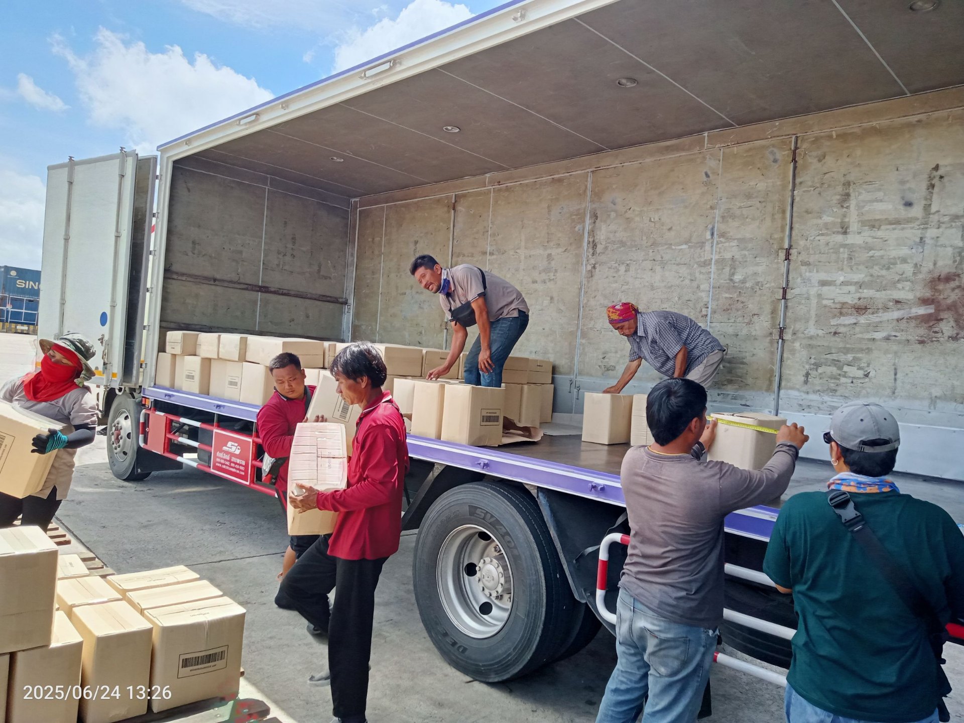 Professional team collaboratively loading cargo boxes onto truck - hands-on logistics teamwork